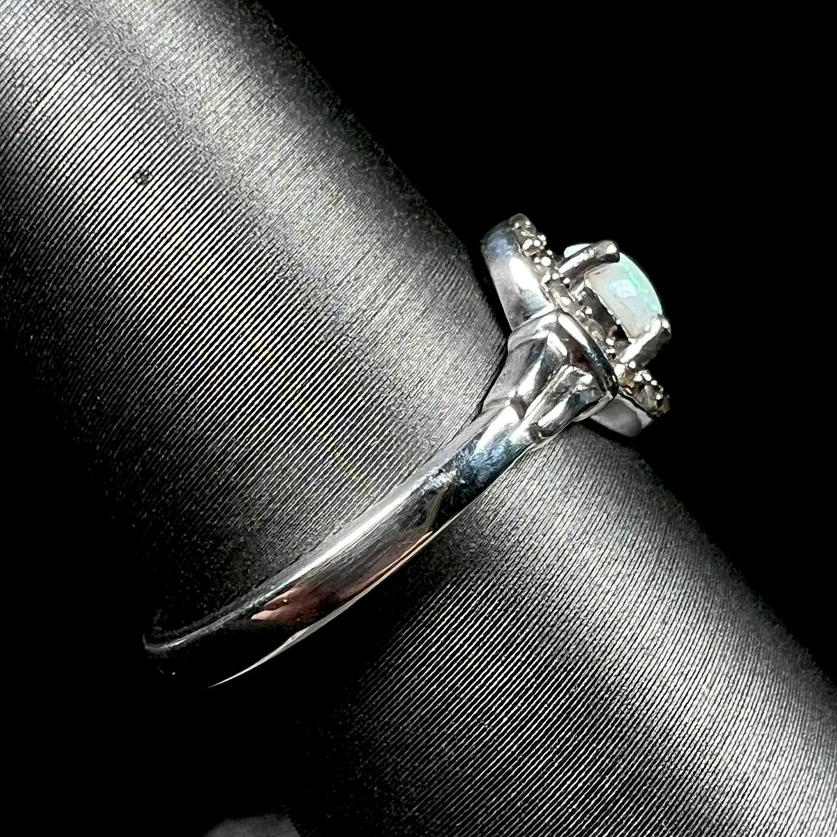 Side view of sterling silver ring set with white opal and smoky quartz accents, shown on ring display; the ring's shank is the primary focus