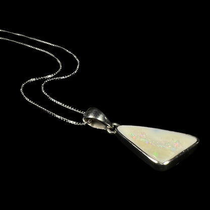 A white Australian boulder opal necklace in .950 silver, laying against a black background, shown at an angle.