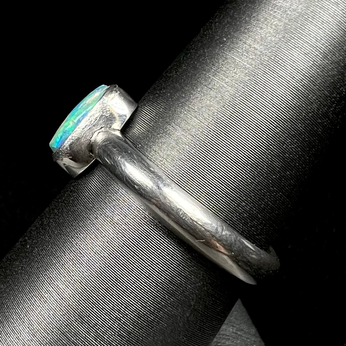 Side view of .999 pure silver opal ring on ring display, focused on ring's handmade shank 