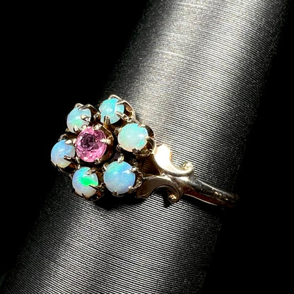 Angled close-up of antique Victorian 9k gold Hungarian opal and pink tourmaline flower ring, shown on ring display