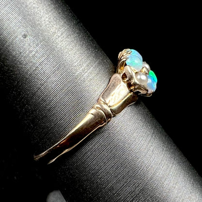 A 9k gold Victorian opal and pearl ring shown on ring display from side view, its polished shank in focus
