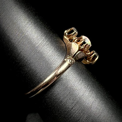 Side view of a 9k gold Victorian opal and diamond ring on a ring display against a black background.