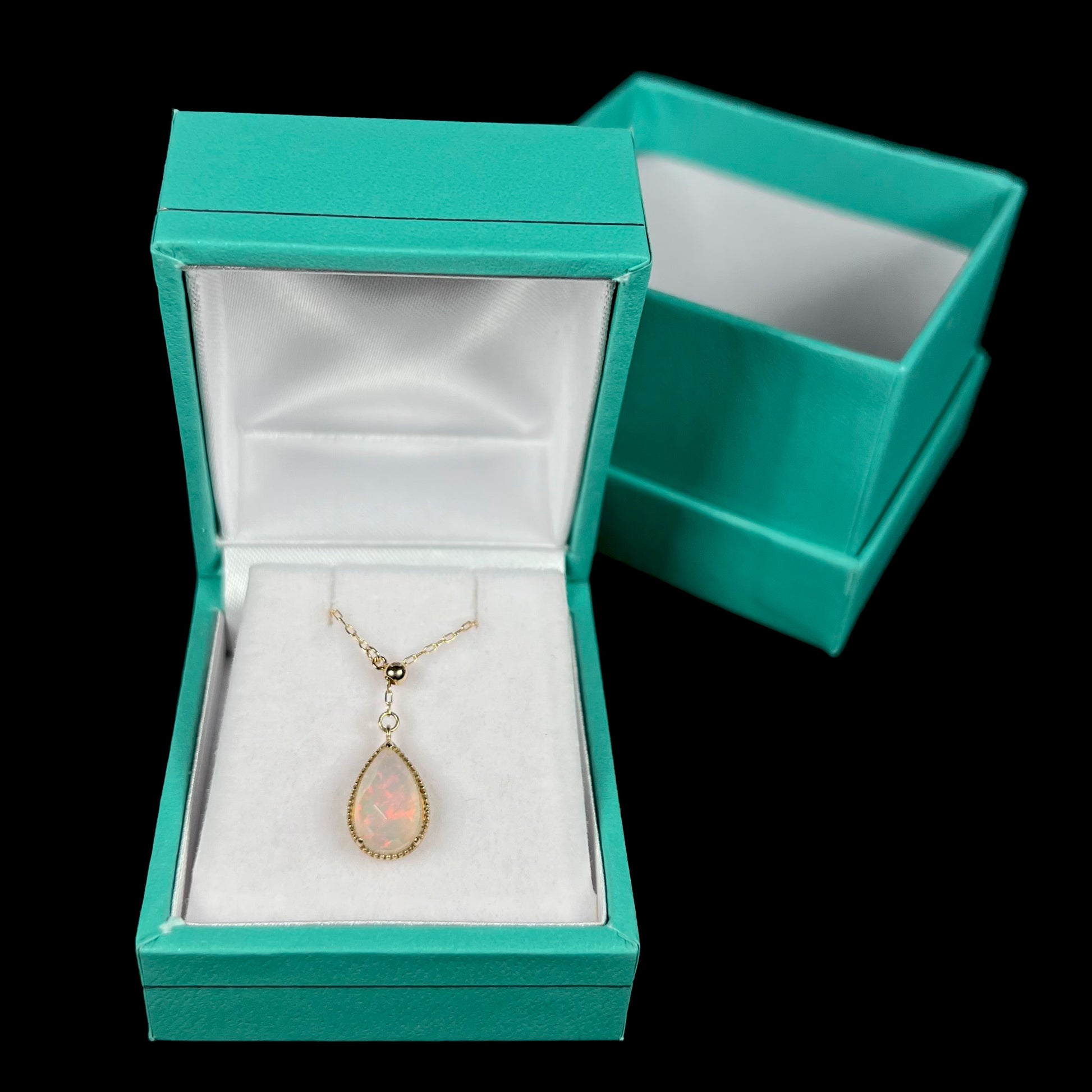 Adjustable opal necklace resting in a blue jewelry box against a black background.