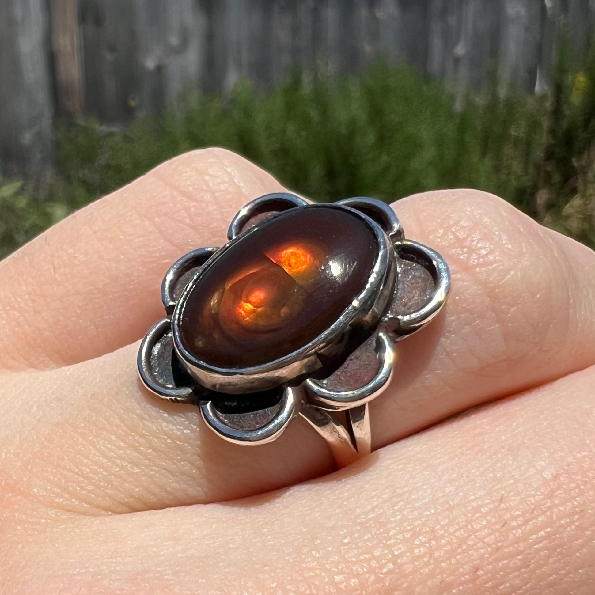 Angled hand shot of ring in sunlight with glowing orange fire.