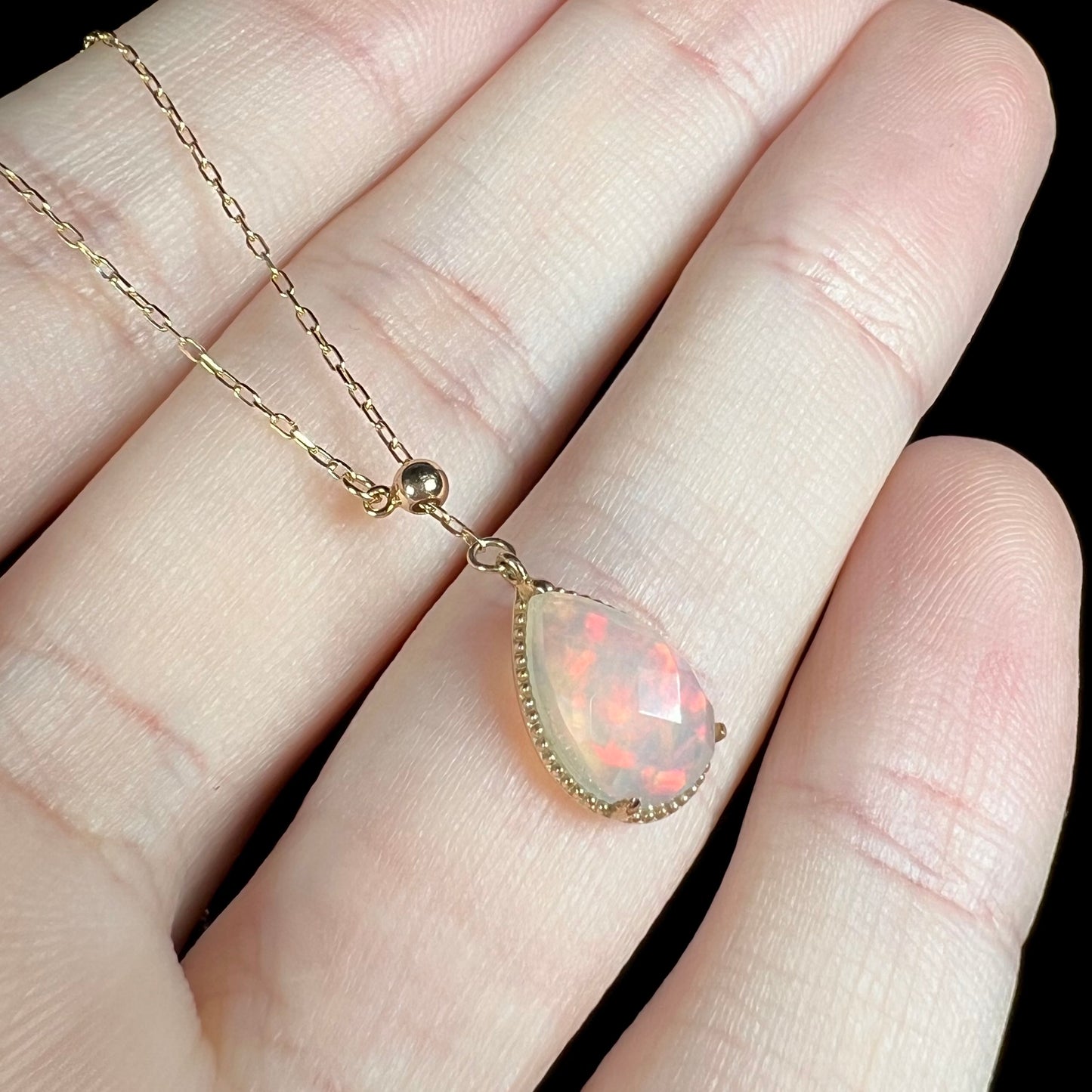 Angled macro view of the opal necklace, with gentle red fire shimmering across the stone.