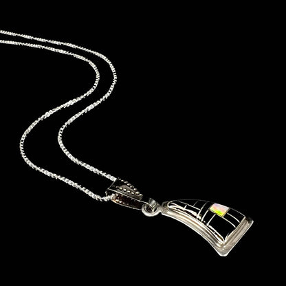 Angled side view of silver necklace with opal inlay on a black background.