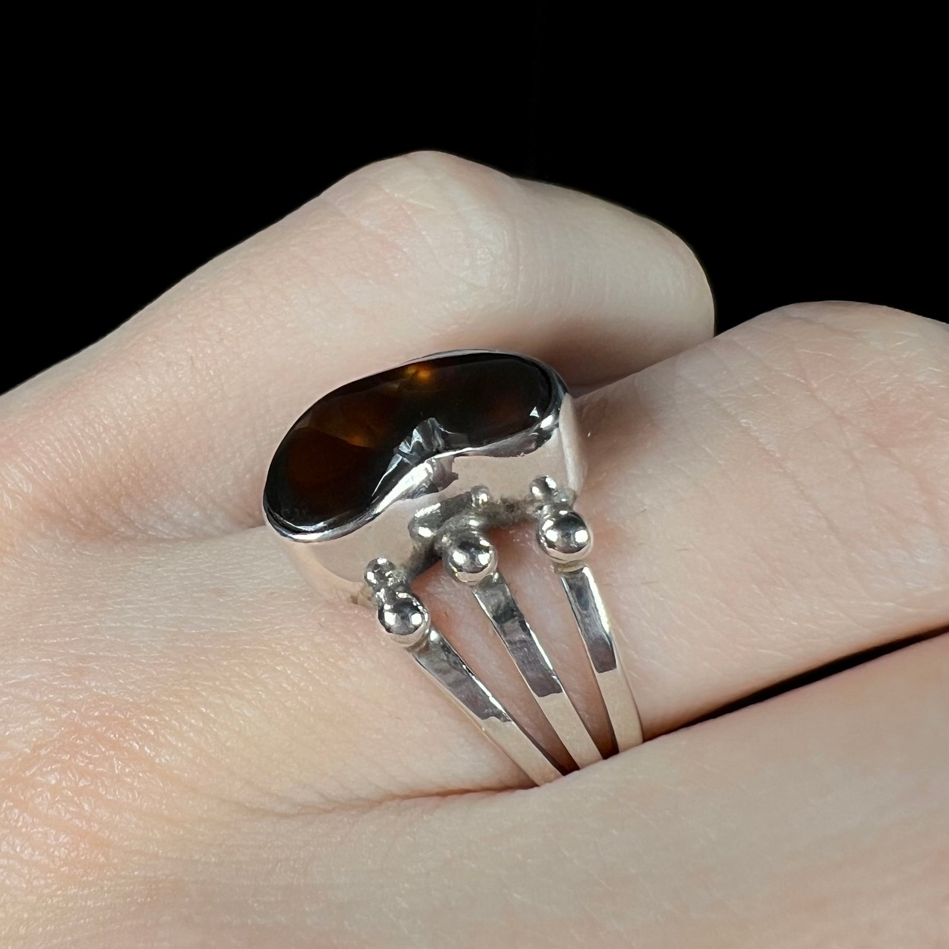 Fire agate ring shown at an angle on fingers with subtle sheen.