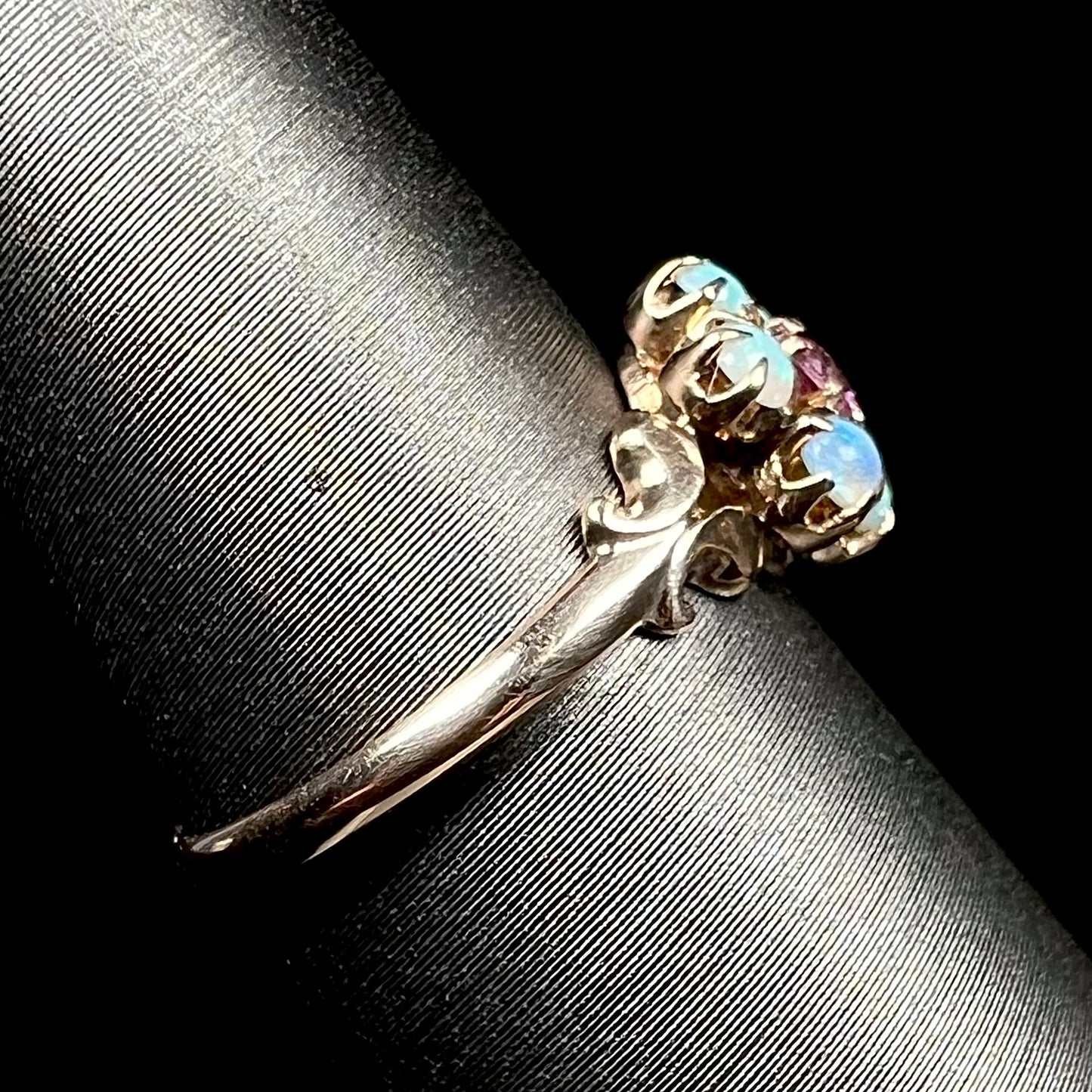 Antique 9k gold opal ring shown on ring display from side view, focused on ring's dainty shank