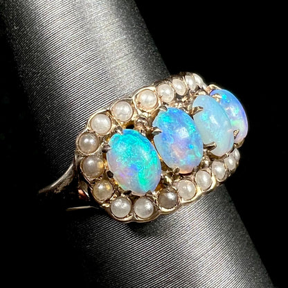 Antique 1880s ring set with four blue Hungarian crystal opals inside of a seed pearl halo, shown from angle on display