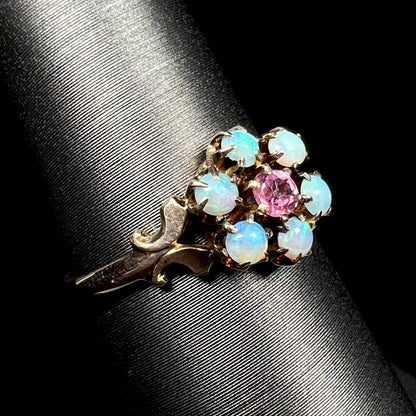 Antique 9k gold ring set with six round Hungarian opals and a pink tourmaline center stone, shown on ring display