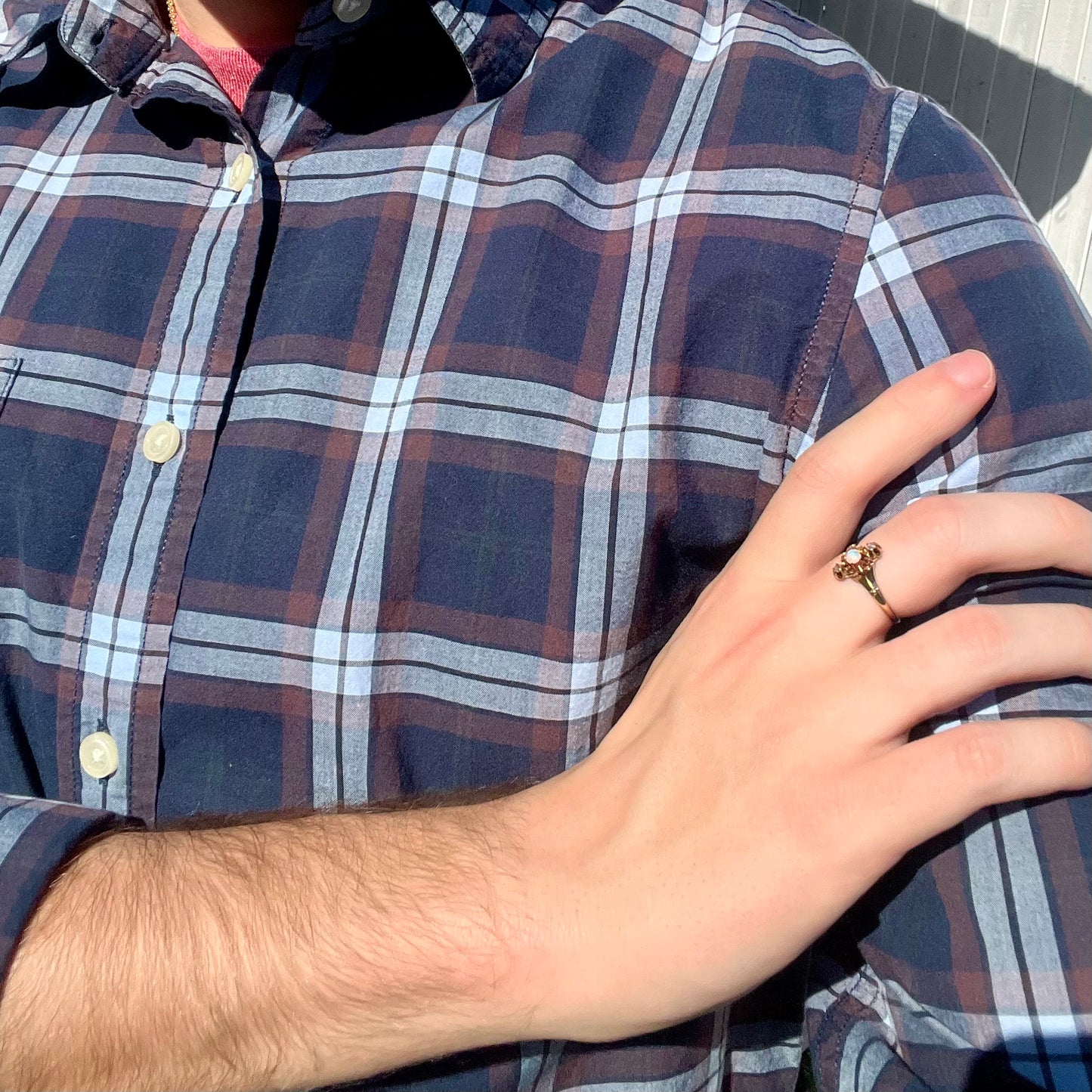 Person wearing a plaid shirt with a hand resting on the shoulder, showing an antique gold opal and diamond ring in sunlight.