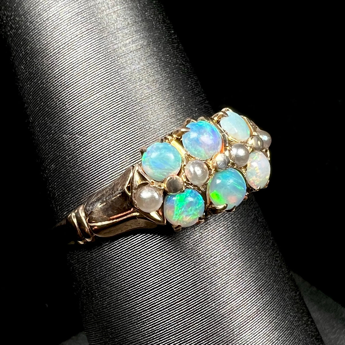 Antique six-stone opal and pearl ring from Victorian era shown close-up from angle on ring display