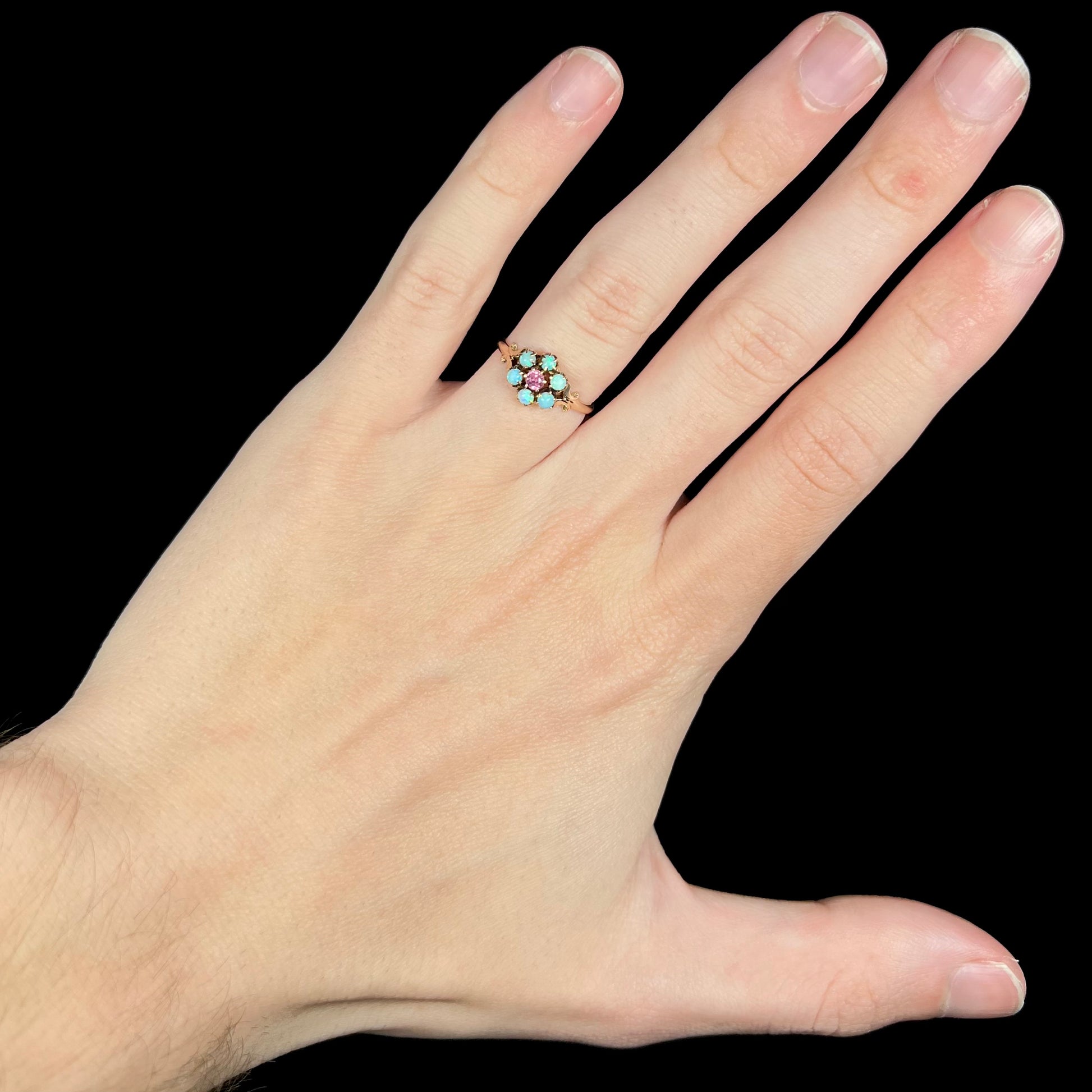 Hand wearing women's antique Victorian opal and pink tourmaline flower design ring