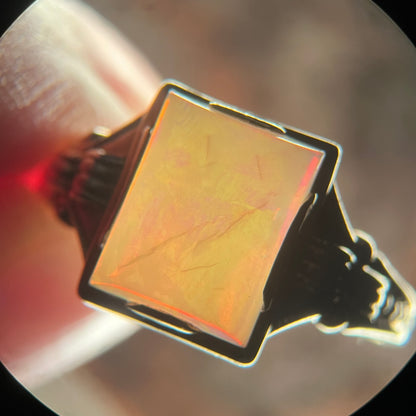 Backlit microscope view of an antique rectangle-shaped opal ring, the backlight showing numerous natural cracks in the opal