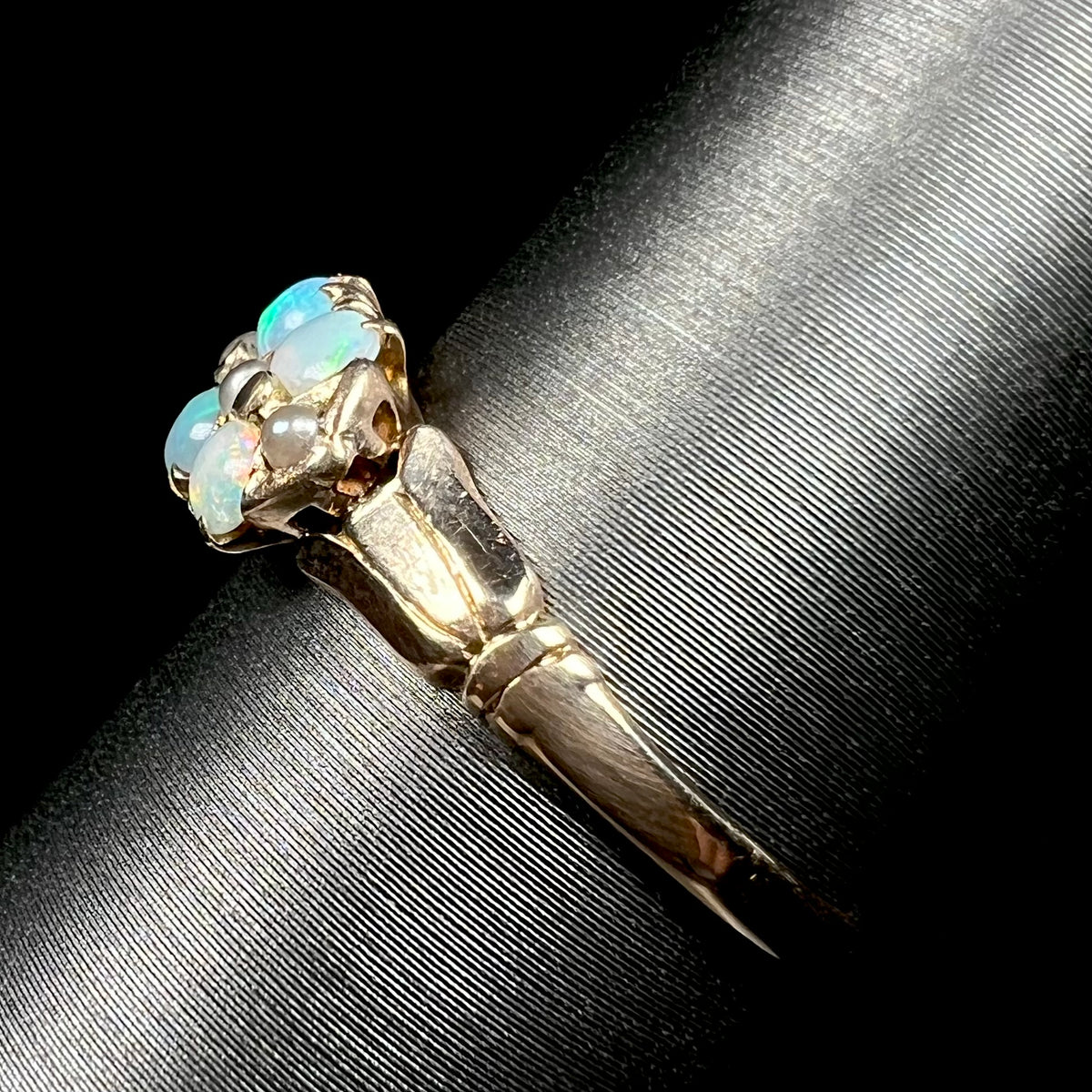Side view of antique 1890s yellow gold opal and pearl ring, shown on ring display; its shank in view