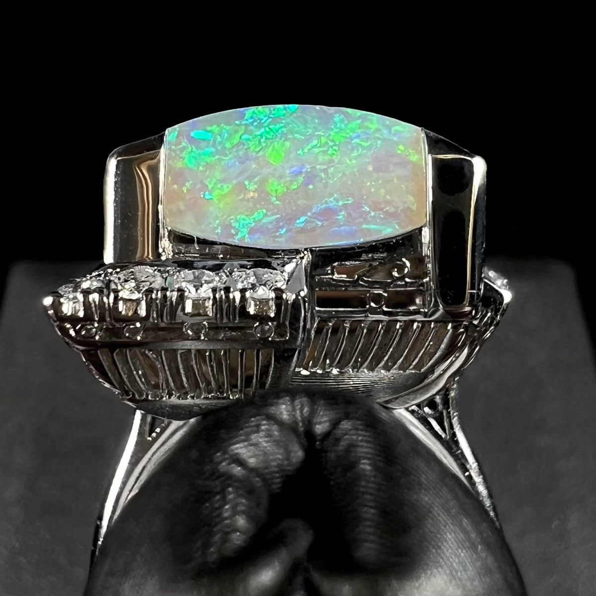 Gallery view of an architectural Japanese platinum opal ring from the Showa era, the thick edge of an Australian light opal sits above open filigree, diamonds, and vertically ribbed basket design.