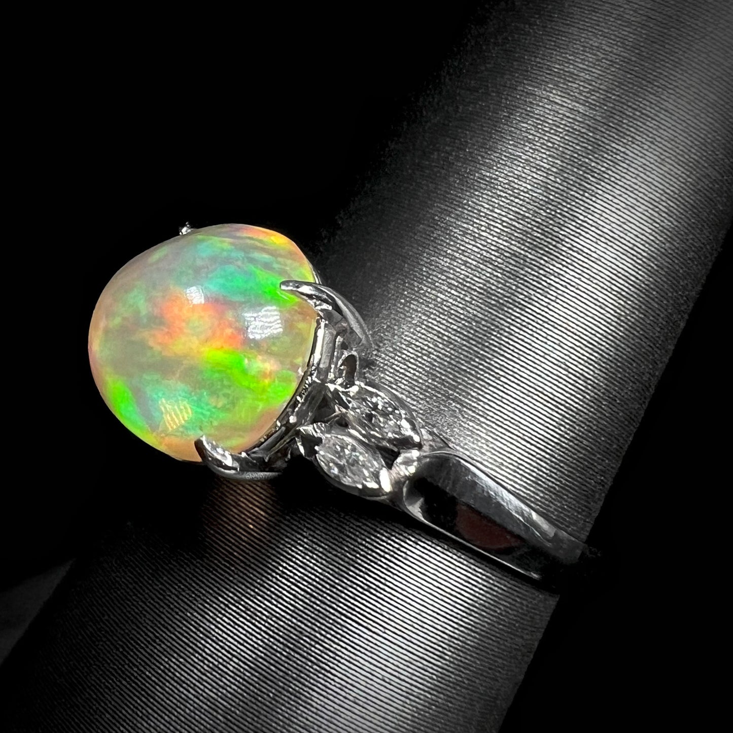 Angled view of an Art Deco-inspired fire opal engagement ring in platinum, featuring a 2.28ct round Mexican fire opal with red and green fire.