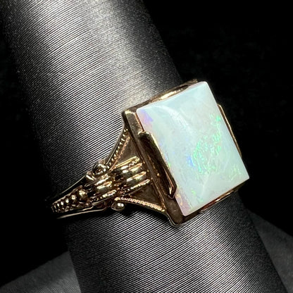 An Art Deco-era 10k gold opal solitaire ring shown close-up from an angle on a ring display