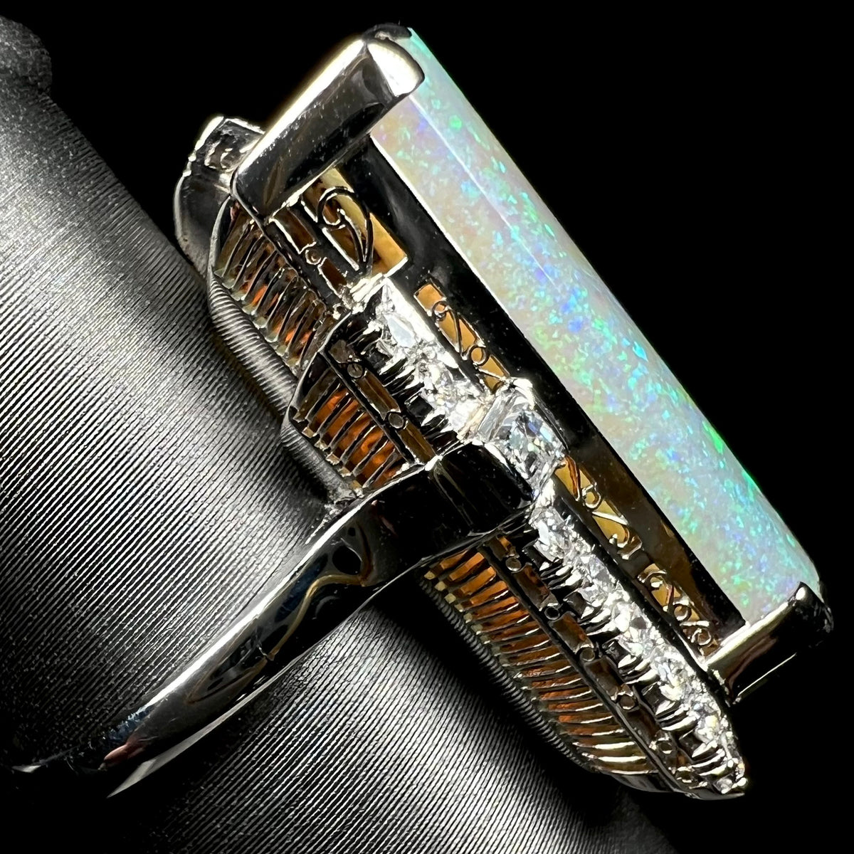 A vintage Japanese platinum cocktail ring with architectural Art Deco-inspired basket design featuring Australian light opal and diamonds, shown from side view.