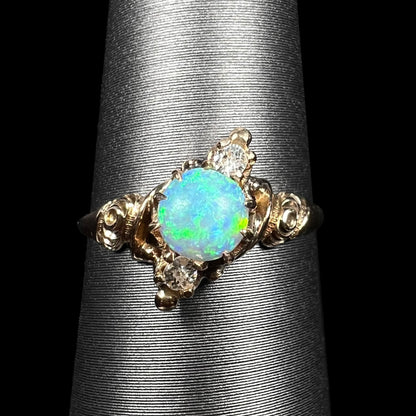 Close-up of antique 10k gold Art Nouveau opal and Old European Cut diamond pinky ring with rose design shoulders, shown on ring display