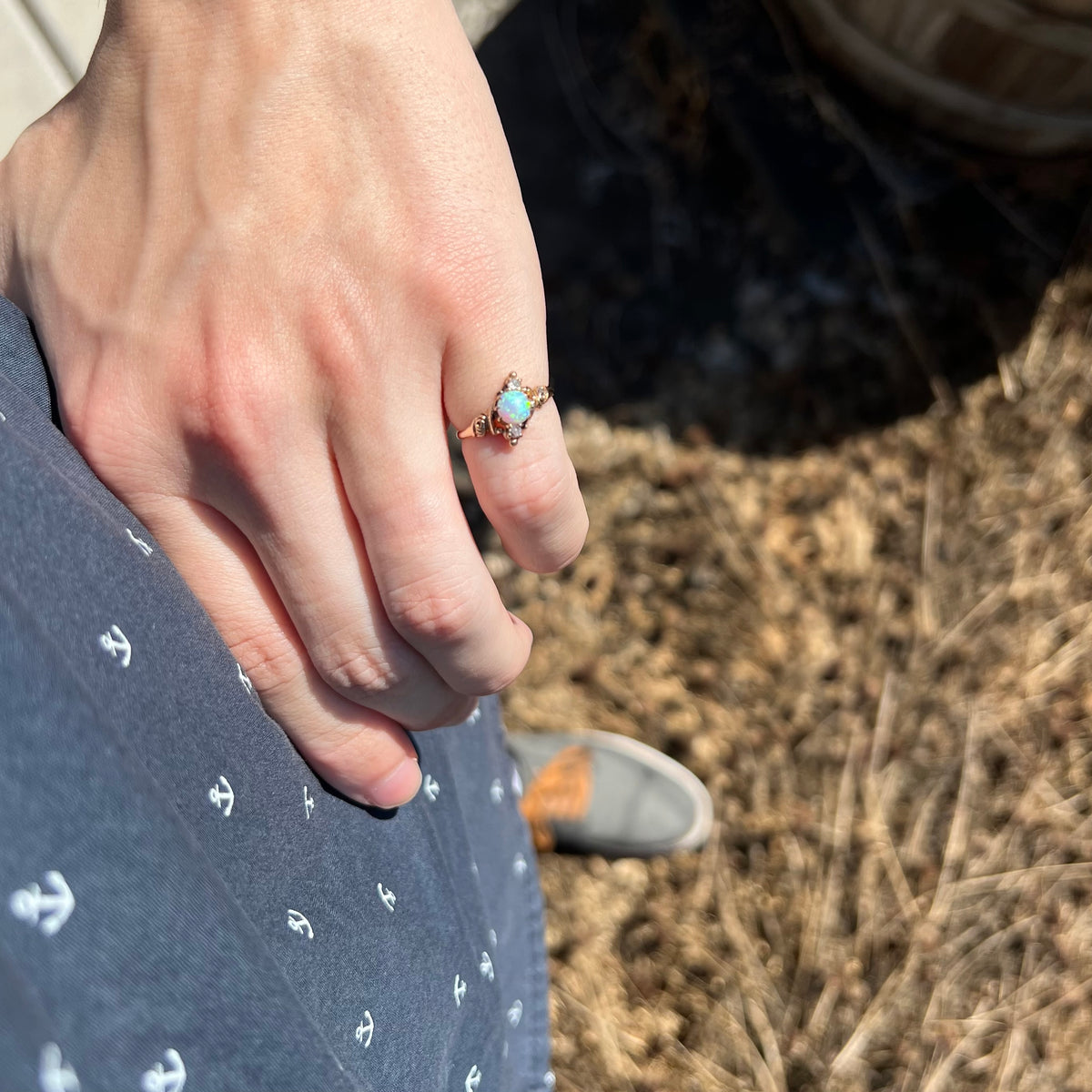 Person's hand resting on hip in sunlight wearing a 10k gold Art Nouveau three-stone opal and diamond pinky ring
