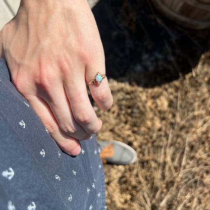 Person's hand resting on hip in sunlight wearing a 10k gold Art Nouveau three-stone opal and diamond pinky ring
