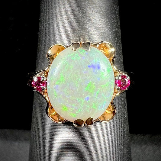 A 1920's Art Nouveau opal and pink sapphire ring.   The ring is yellow gold and palladium.  The opal is green and purple.