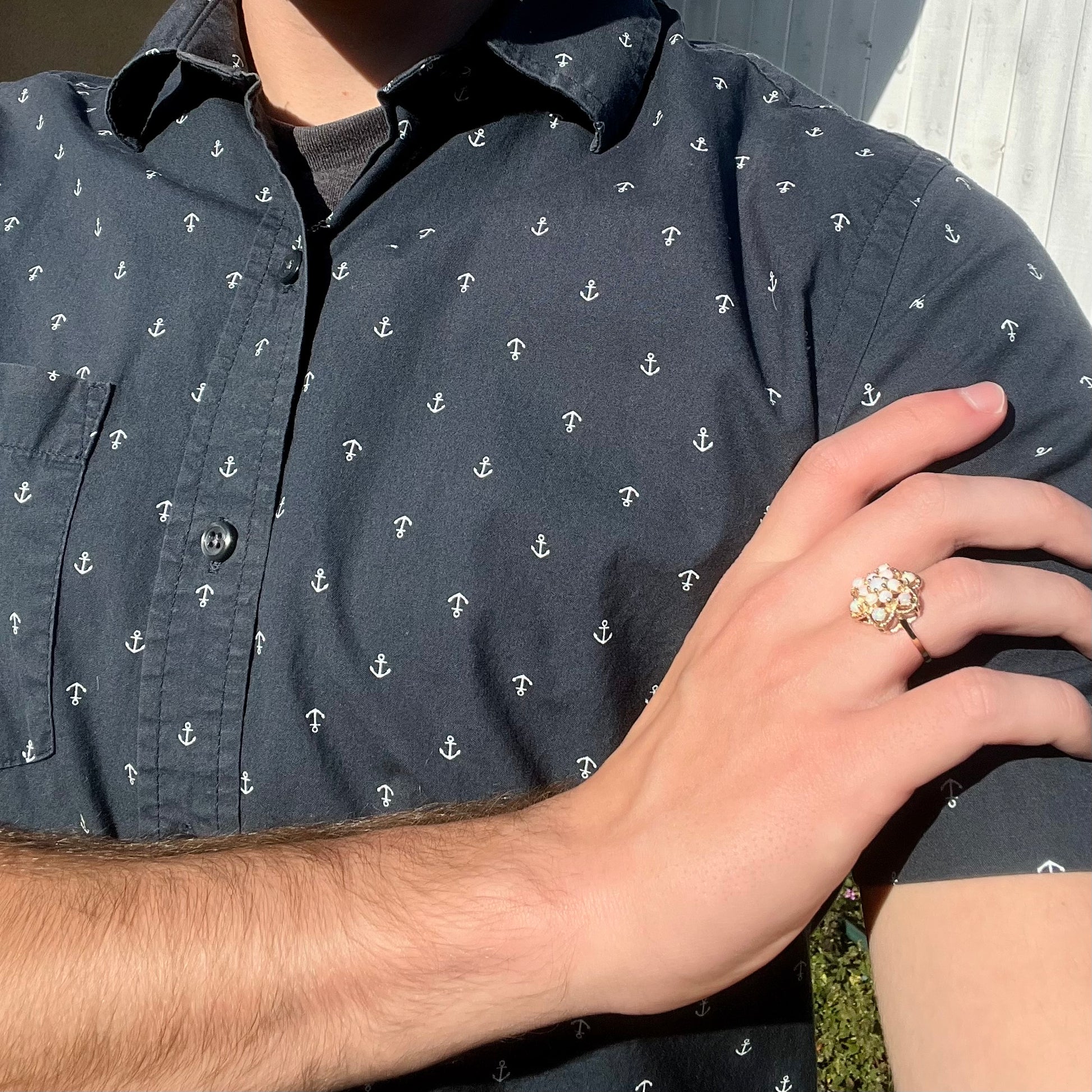 A hand wearing an atomic-inspired opal cluster ring in the sunlight, as the hand rests on the model's opposing shoulder.