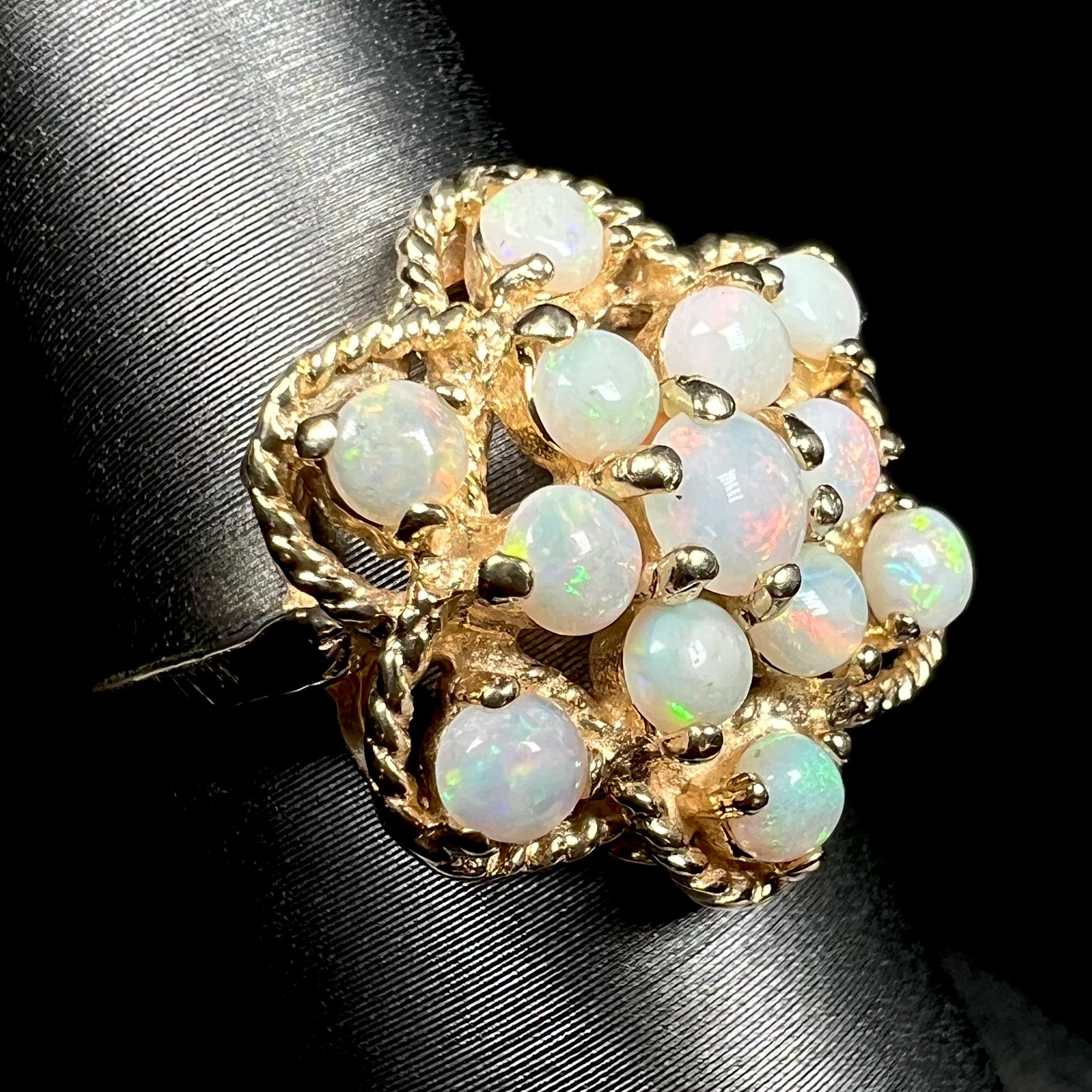 Close-up angled view of an atomic-inspired vintage Australian opal cluster ring made by J.M. Fox, shown on a ring display against a black background.