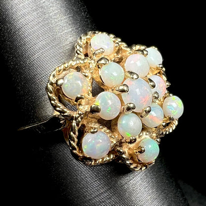 Close-up angled view of an atomic-inspired vintage Australian opal cluster ring made by J.M. Fox, shown on a ring display against a black background.