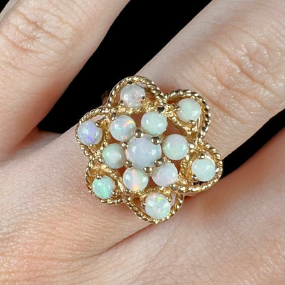 Close-up top-down view of an atomic-style opal cluster ring made by J.M. Fox in yellow gold, shown on a finger.