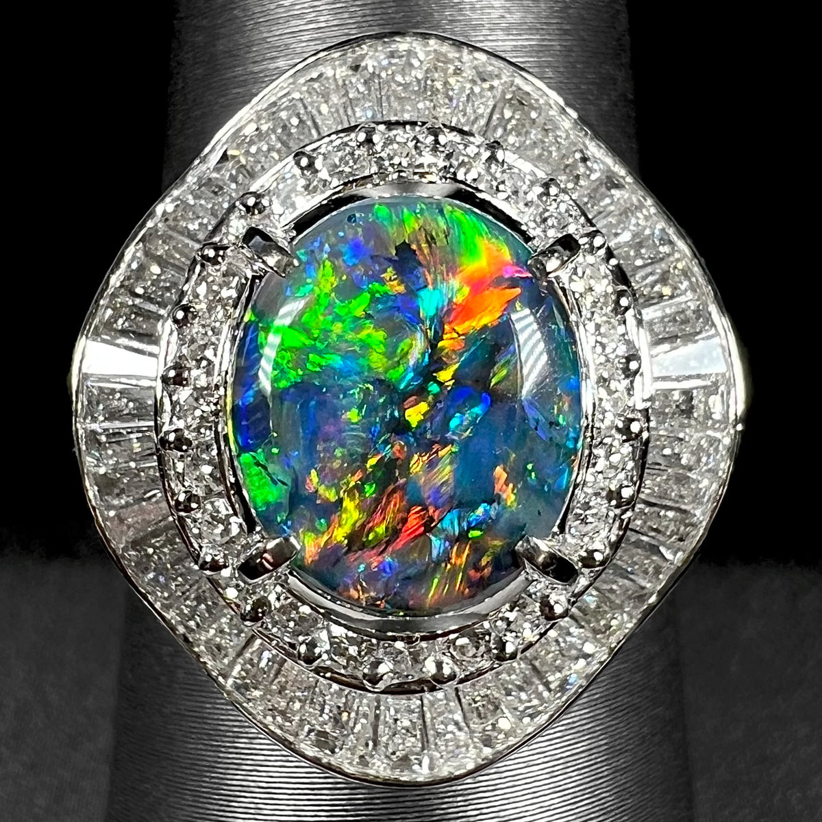 Close-up of vintage Japanese platinum ballerina ring with a 2.58ct multicolor Australian black opal and 1.38ct diamond surround, shown on ring display.