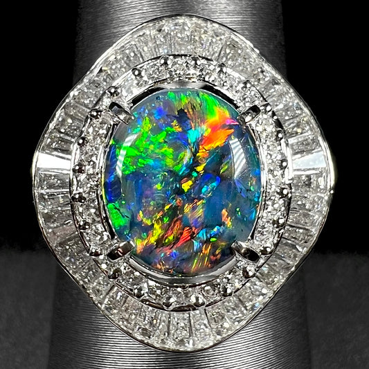 Close-up of vintage Japanese platinum ballerina ring with a 2.58ct multicolor Australian black opal and 1.38ct diamond surround, shown on ring display.