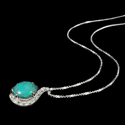 Women's Australian black opal and diamond necklace shown laying on black background, its chain flowing behind the pendant.