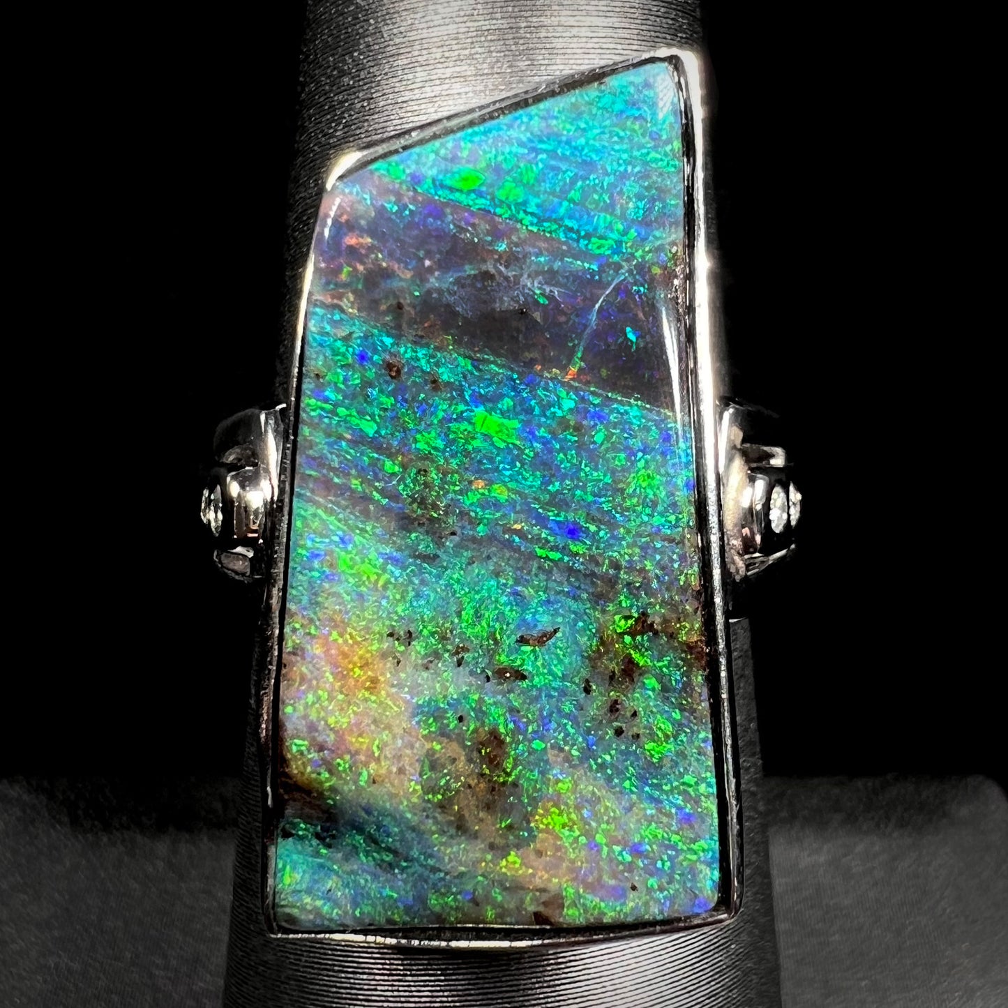 An 11.67ct Australian boulder opal and diamond ring in platinum with green color play, shown on a ring display.