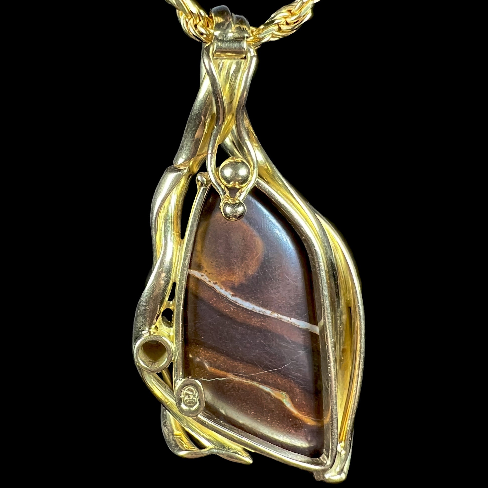 Back side of open-back Modernist-style gold Australian boulder opal pendant. The opal's ironstone matrix and pendant's enhancer bail are visible.