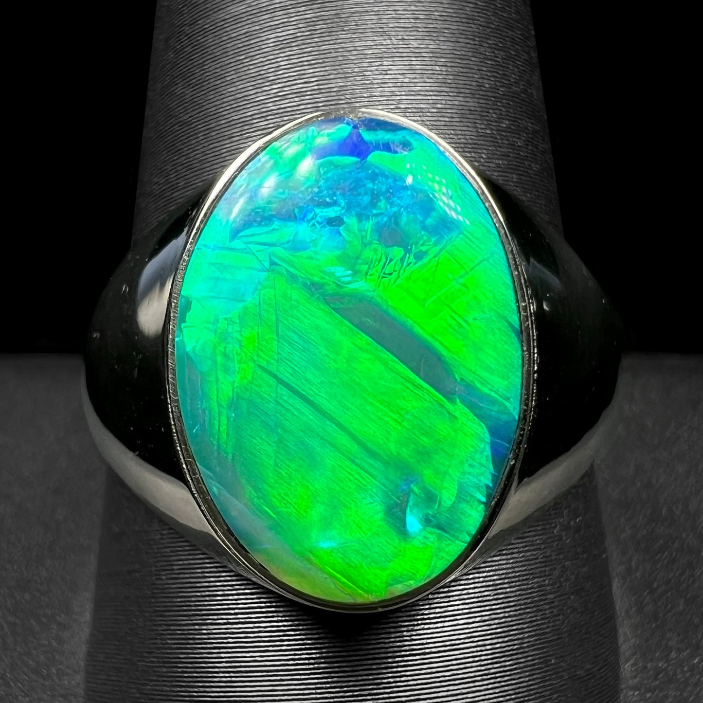 Close-up of white gold Australian crystal opal mens ring with green flash on ring display