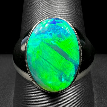 Close-up of white gold Australian crystal opal mens ring with green flash on ring display