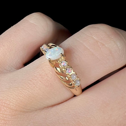 Angled close-up of an Australian opal crisscross ring in yellow gold, shown on a finger.