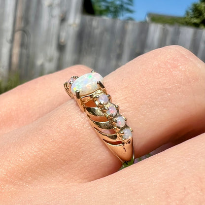 Angled close-up view of an Australian white opal crisscross ring worn on a finger in the sunlight.