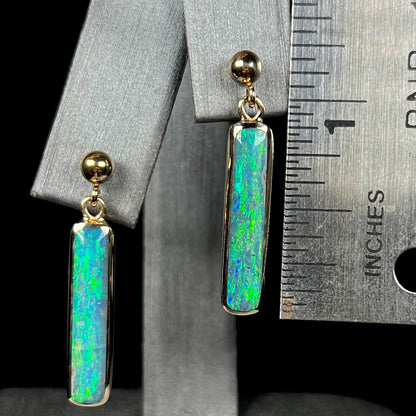 Australian opal dangle earrings shown next to a ruler, measuring 1.25 inches in length.