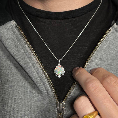 An Australian opal and diamond necklace made from platinum, worn around a neck.  The opal has red flashes.