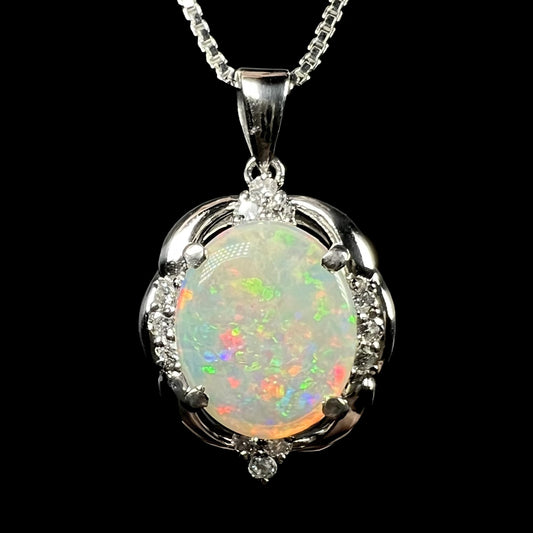 An Australian opal and diamond pendant made from platinum, shown from the front against black background.