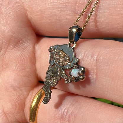 Round Australian opal Dora the Explorer pendant shown close-up in a hand held at an angle in natural light.  The opal has subtle green play of color.