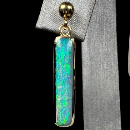Close-up of a single Australian opal drop earring with crack and naturally occuring gray potch inclusion.