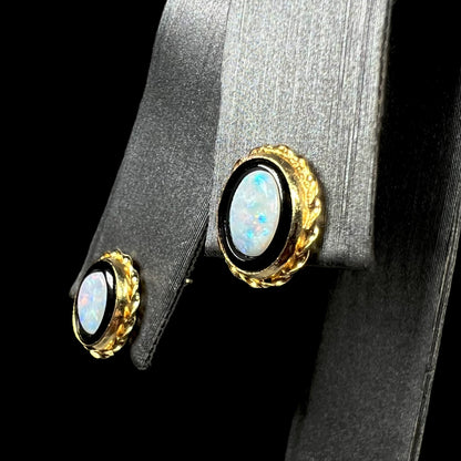Australian opal in onyx stud earrings with gold rope bezel design shown on earring display from angle.