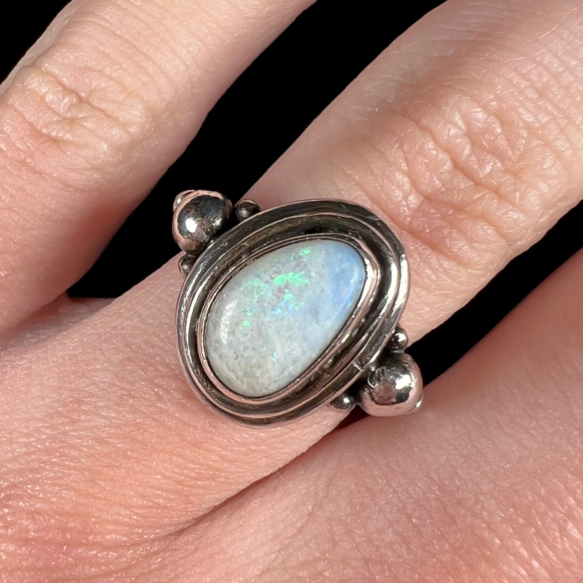 Close-up of a handmade Boho-style sterling silver opal ring set with an Australian opal, worn on a finger.