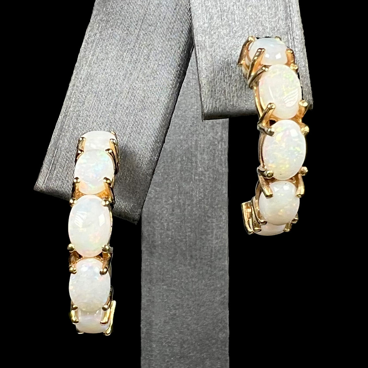 A pair of large 14k yellow gold five-stone Australian white opal semi-hoop earrings on earring display