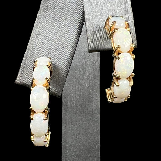 A pair of large 14k yellow gold five-stone Australian white opal semi-hoop earrings on earring display
