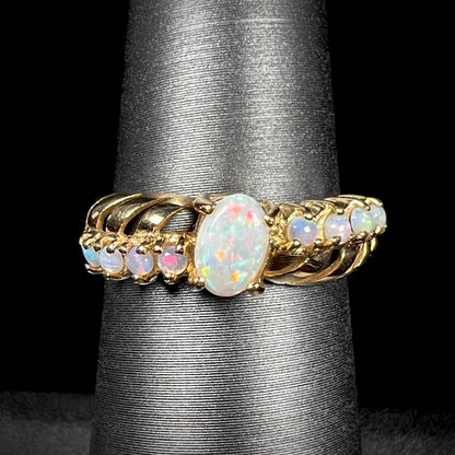 A yellow gold ring featuring two crossing, alternating lines of round cut Australian opals.  In the middle is a larger oval cut Australian opal.